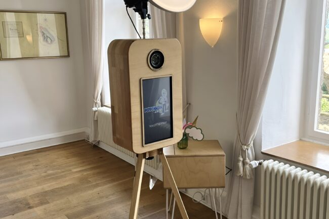 Gäste lachen vor der Vintage Fotobox in der Burg Heppingen, während im Hintergrund frisch gedruckte Fotos aus dem Drucker kommen. Fotobox-AW.de sorgt für Spaß und Erinnerungen in Bad Neuenahr-Ahrweiler.