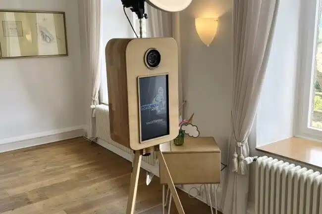 Gäste lachen vor der Vintage Fotobox in der Burg Heppingen, während im Hintergrund frisch gedruckte Fotos aus dem Drucker kommen. Fotobox-AW.de sorgt für Spaß und Erinnerungen in Bad Neuenahr-Ahrweiler.